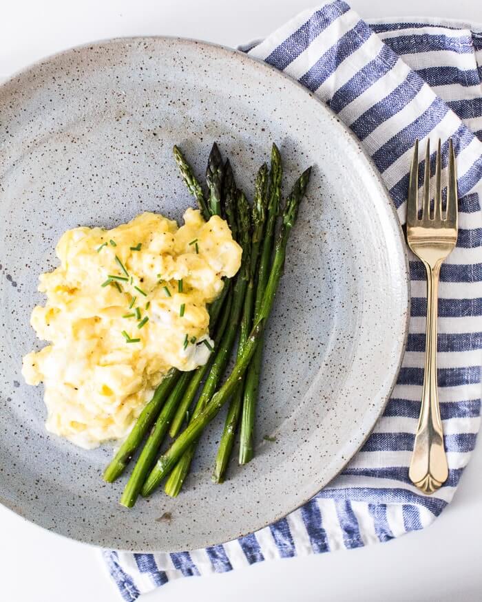 Fluffy scrambled eggs on a plate with asparagus